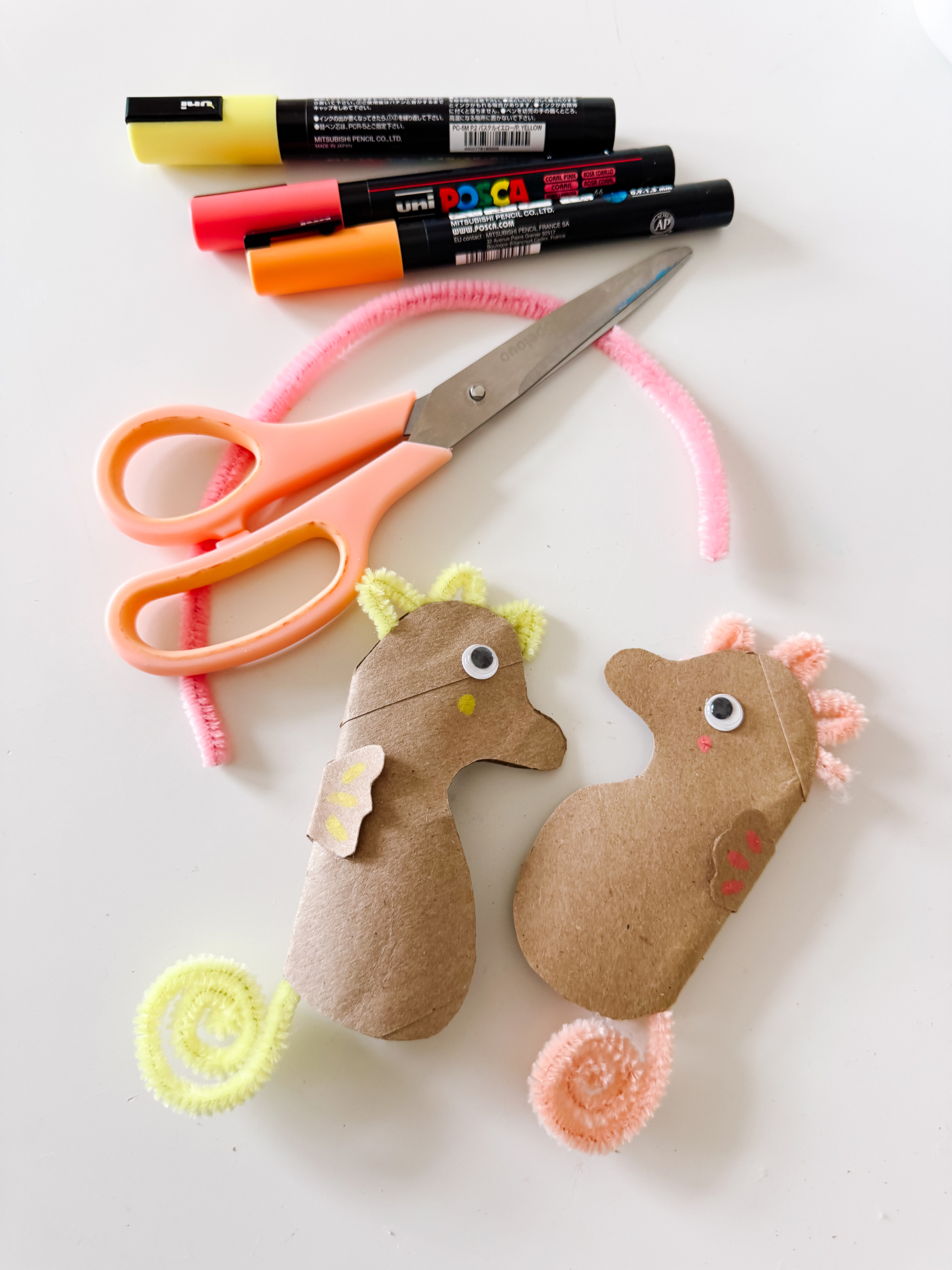 Markers, scissors, pipe cleaners, and cardboard seahorse cutouts on a table