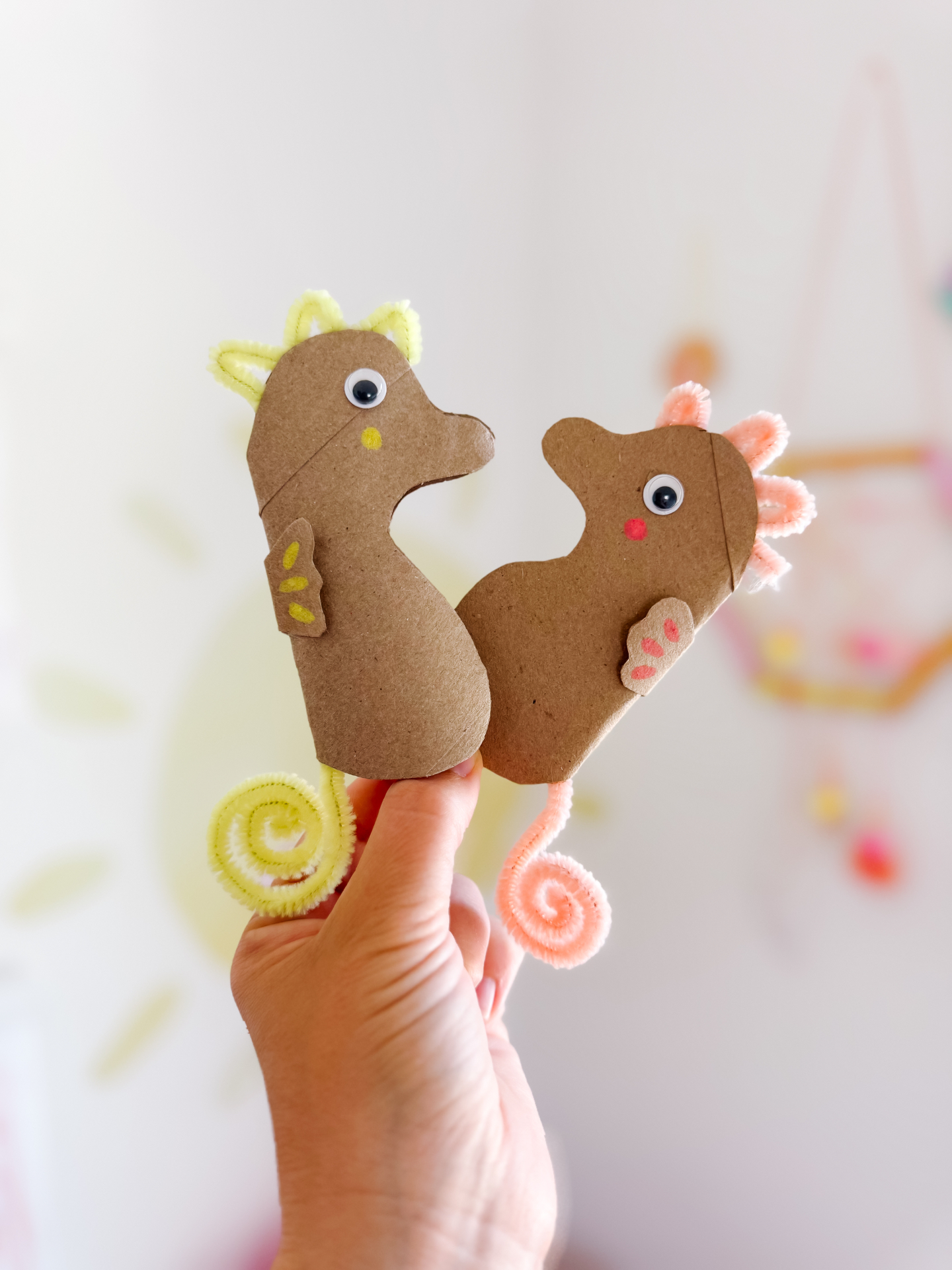Close-up of two decorated cardboard seahorses held in a hand