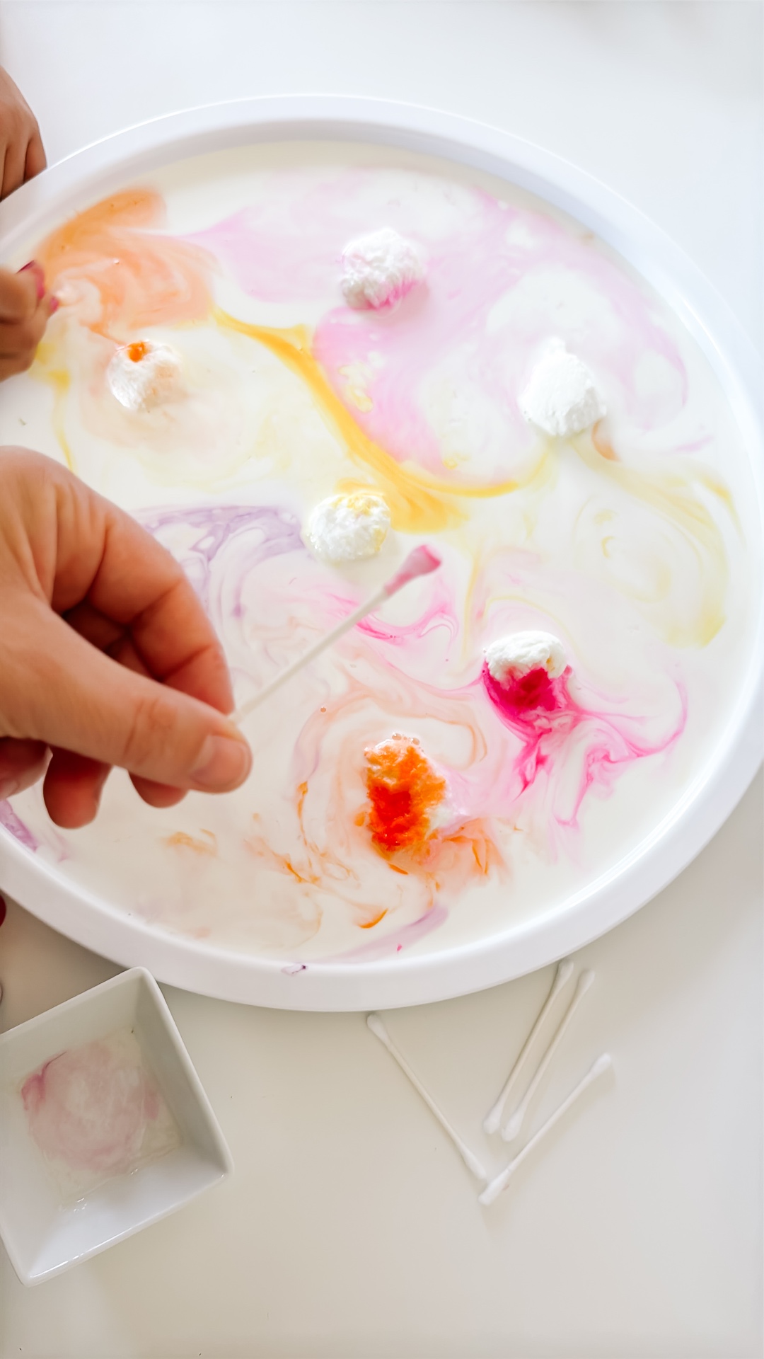 Pink, orange, and yellow colors arranged across a tray of milk