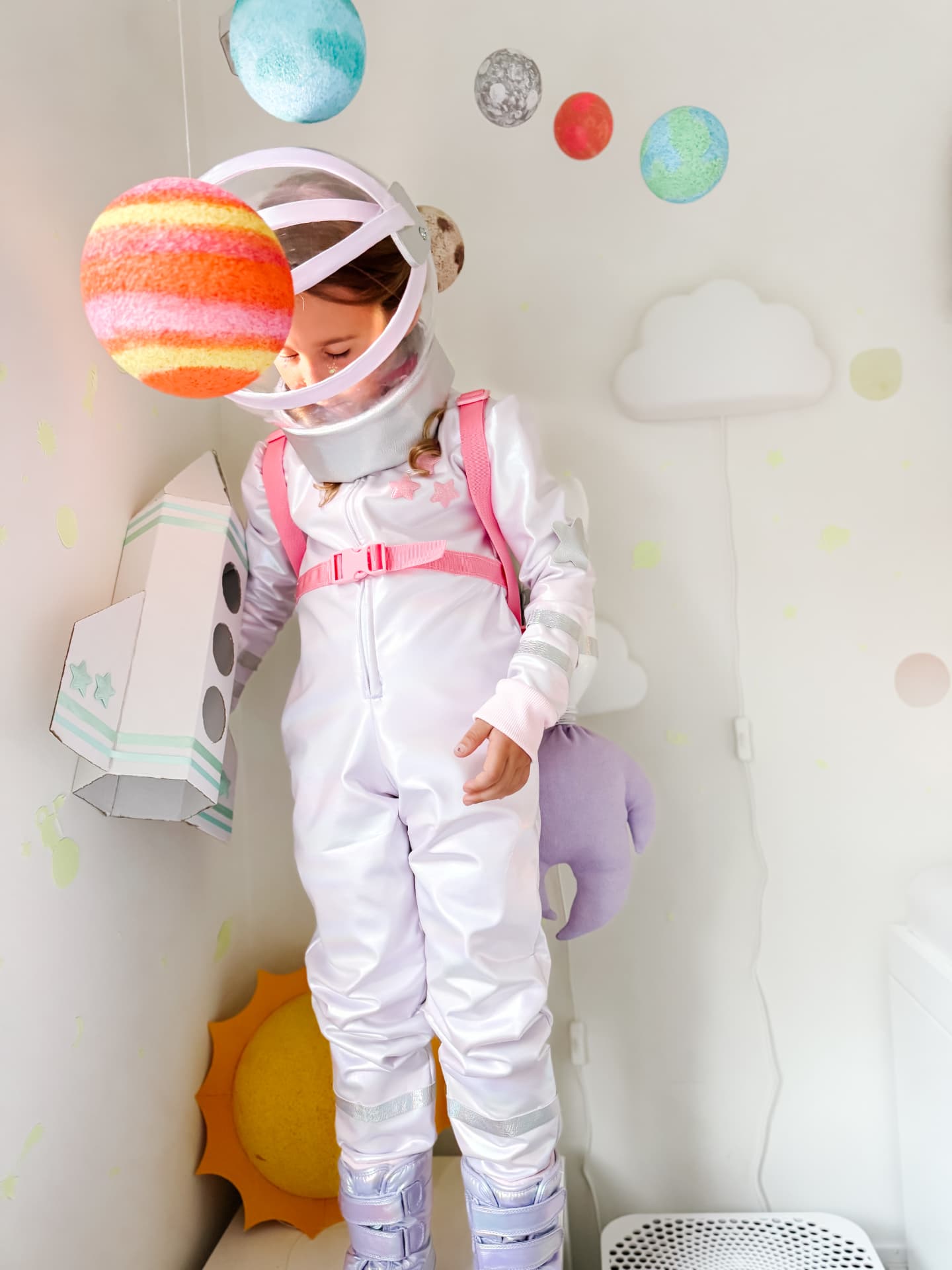 Child wearing a handmade pink and purple astronaut costume with a clear helmet and rocket jetpack