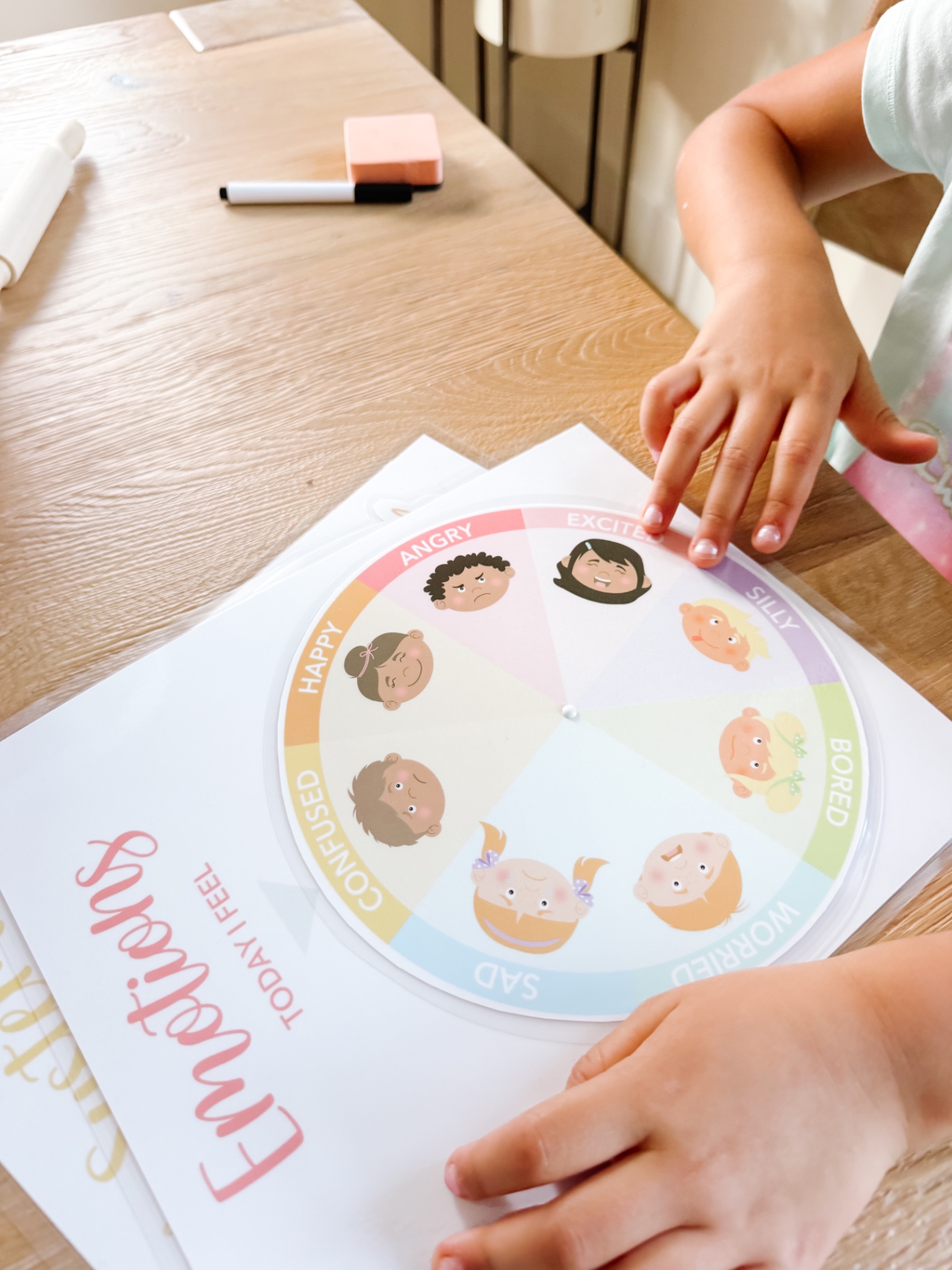 Child turning an emotions wheel showing happy, sad, worried and excited faces