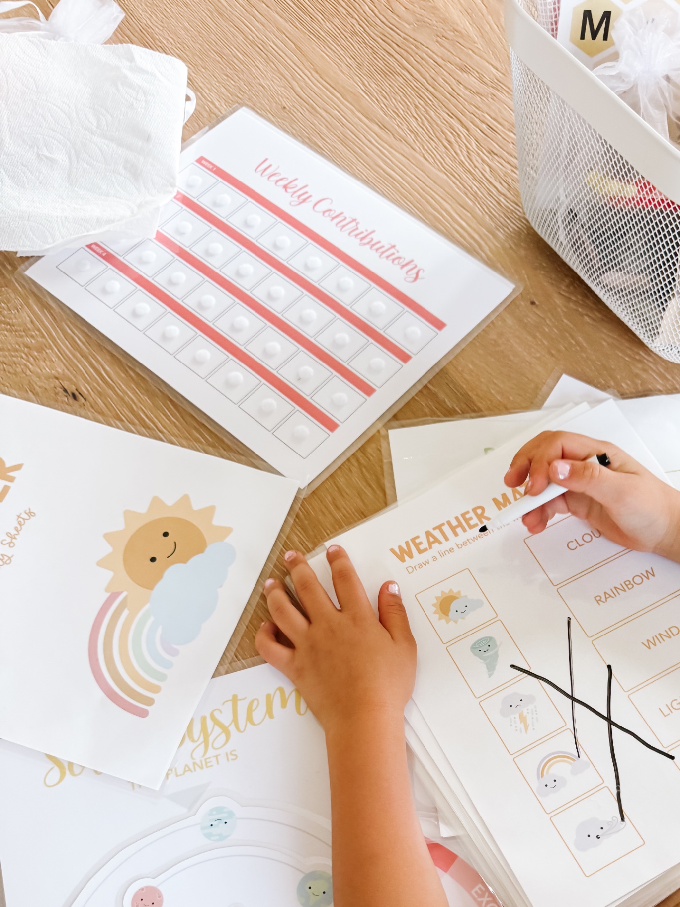 Child using a dry erase marker on a weather matching activity sheet